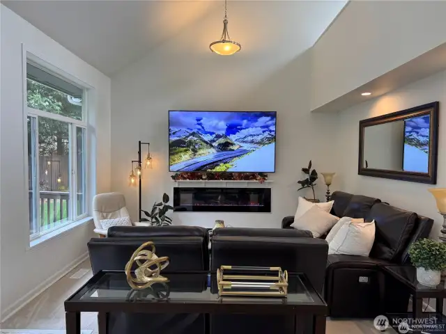 Bright and inviting family room with soaring vaulted ceilings, large windows for natural lighting, and an open, airy feel - perfect for relaxing or entertaining.