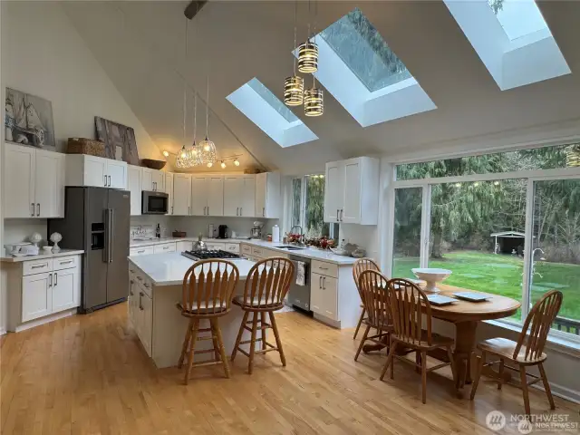 Beautiful open-concept kitchen featuring three custom skylights and expansive windows that fill the space with natural light, while offering stunning views of the park-like grounds - perfect for everyday living and entertaining.