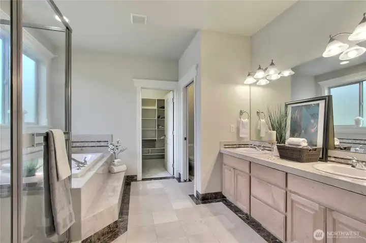 The large, solid French doors offer a grand and elegant entrance into your marbled, spa-like retreat. This atmosphere is thoughtfully designed to pamper and refresh.   The deep jetted tub is for soothing hydrotherapy, a large glass shower, and a private water closet for added comfort and discretion. Completing this space is an extremely spacious walk-in closet, beautifully outfitted with custom built-ins to keep everything organized and within reach. Your personal sanctuary is tucked within the heart of the home.