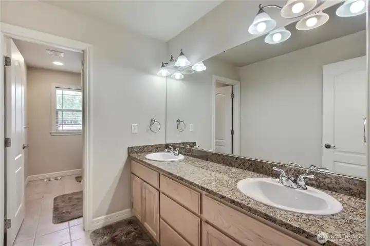 The upper floor shared full bath is thoughtfully designed with a door separating the double vanities from the shower and toilet area. This layout adds privacy and convenience, allowing multiple people to use the space comfortably at the same time.