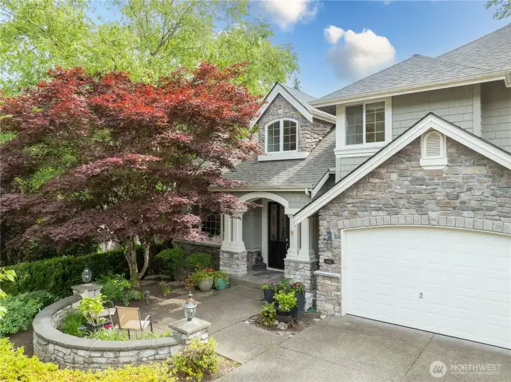 Welcoming front entry with beautiful stonework, lush landscaping, and a private garden approach—offering timeless curb appeal in The Highlands