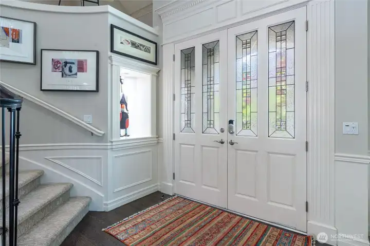Inviting entry with decorative glass double doors, classic millwork, and a built-in art alcove—creating a refined and memorable first impression.