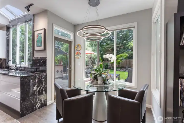 Bright dining nook adjacent to the kitchen, surrounded by windows and overlooking the private backyard—perfect for casual meals and indoor-outdoor flow