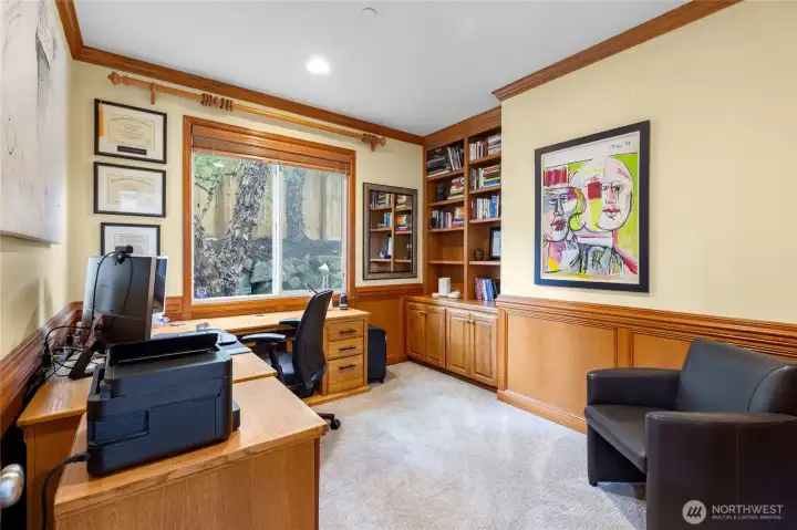 Private main floor office with custom built-ins and workspace nestled by trees