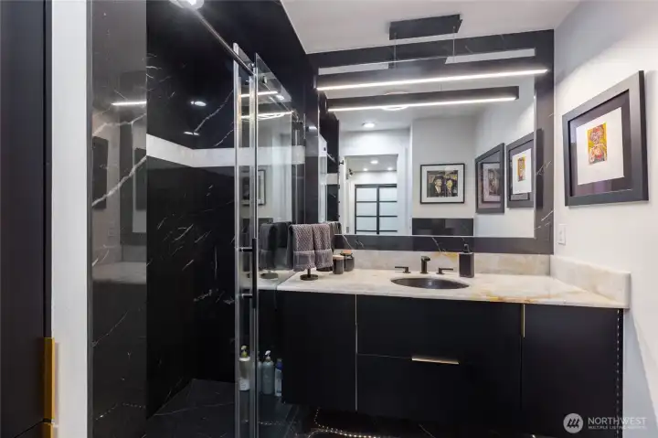 Designer bathroom renovation featuring modern cabinetry, statement lighting, and upscale materials.