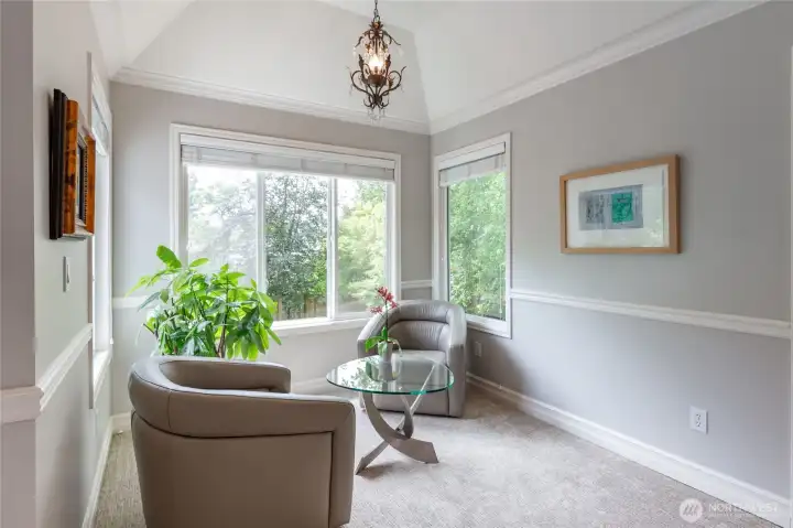 Light-filled sitting area within the primary suite with large windows and lush views.