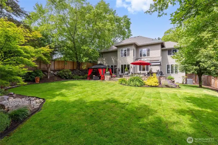 Lush, private yard with mature landscaping, manicured lawn, and serene water feature creates a peaceful retreat.