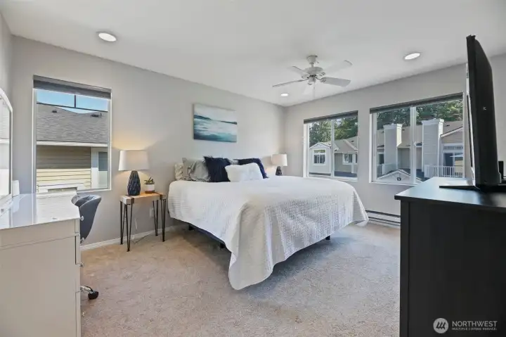 This spacious primary bedroom has room for everything. One of the best parts is that this is an end unit and has several large windows so it feels very bright in the home.