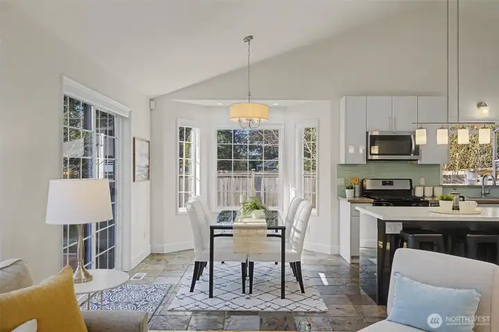 A charming dining nook is wrapped in windows and anchored by a bay window that fills the space with natural light. Enjoy peaceful views of the backyard, paver patio, gazebo and garden area—an inviting spot for morning coffee, casual meals or relaxed evening gatherings.