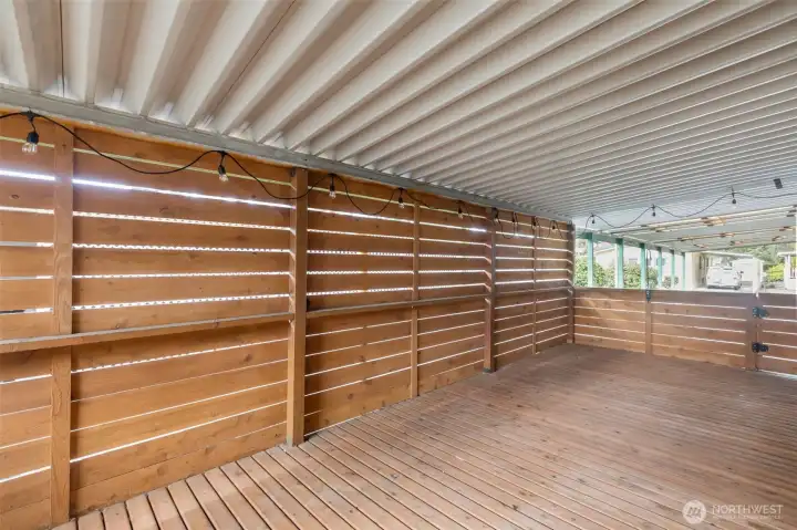 The Deck has been privatized by creating a horizontal cedar slat wall that actually acts as a wind barrier when its cooler outside, a shield when it's raining sideways, a wall that use to hang decor or otherwise, and a visual barrier from the neighboring property.  There are 2 gated access points on either side of the deck; One from the 3-car carport and heading to the storage shed/backyard.