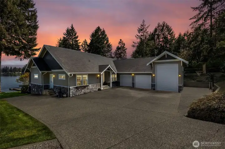 The wide driveway isn’t just for show, it actually works. Pull right up next to the mudroom door for easy unloads, park a boat or trailer along the side, and still have room for guests to come and go without the usual shuffle. The three-car garage includes an RV-height door, and yes, you still catch a glimpse of the water as you come down the drive. The exterior brings it home with stone accents grounding the base and Hardiplank siding above for durability that looks good long-term.