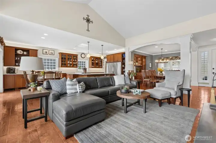The vaulted living room opens up in front of you, while the dining area is framed by those arched openings and pillars that give it definition without closing it off. To the left, the kitchen stretches out in a way that feels ready for real life, plenty of space to cook, gather, and keep things moving without bottlenecks. Even where the ceilings aren’t vaulted, you’ve still got 9-foot height carrying that open, airy feel through the kitchen and dining spaces. And then there’s the 8-foot front door in the distance, quietly setting the tone with a sense of scale and presence that makes the whole home feel just a little more elevated.