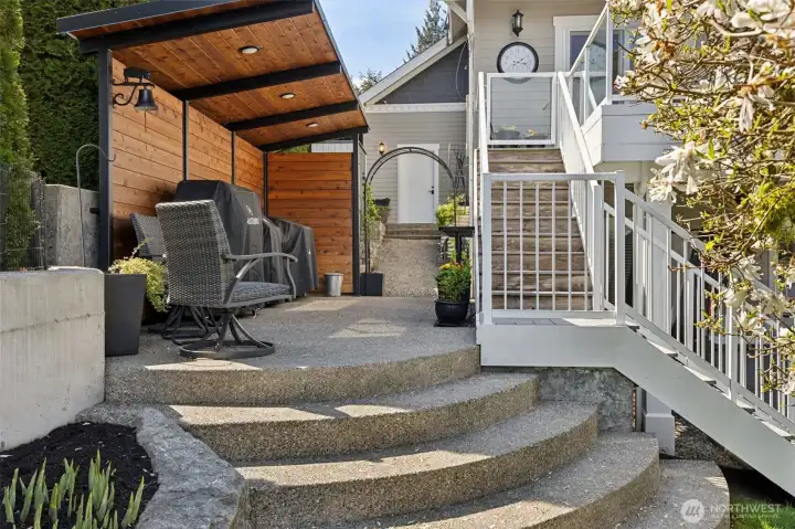 A fully covered custom BBQ area with wood plank walls gives it that cozy, tucked-in feel while still being completely functional, built-in lighting means you’re grilling whether it’s sunny, raining, or somewhere in between. No cancellations here. The arched steps lead you right down to the lawn, keeping everything connected and easy to navigate, and just up the path you’ve got direct access to the garage. And for anyone with pets or little ones, there’s a swinging gate at the top of the stairs that keeps things contained without sacrificing the flow.