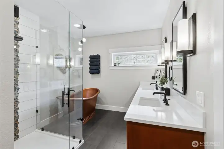 The layout flows effortlessly, with the freestanding tub and glass-enclosed shower positioned for that true spa-like feel. The double vanity offers kitchen-height quartz counters, giving you space to spread out without feeling crowded, and sleek medicine cabinets above each sink keep storage streamlined. A high-set window brings in natural light while maintaining privacy. And let’s not overlook what you don’t see, radiant floor heating underfoot, not just here but in all bathrooms throughout the home.