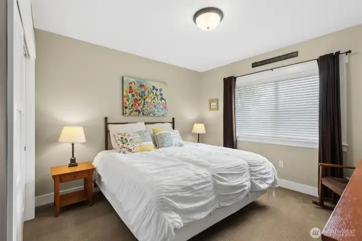 Currently set up as a sleeping area, this lower-level den works beautifully for guests, extended stays, or whatever your situation calls for. The durable Berber carpet in a warm oatmeal tone keeps it practical and comfortable, while the soft, latte-inspired wall color keeps things light without feeling stark. Wide-slat blinds add privacy and control over natural light, making it easy to adapt the room to your needs. While the home is on a two-bedroom septic, the layout offers multiple flexible spaces like this one, giving you room to live a little more expansively.