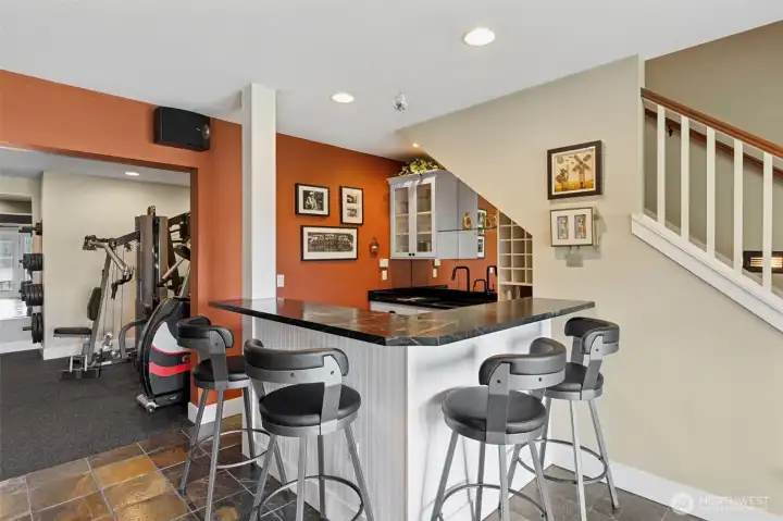Now this is how you do a lower level. Seating for four at the bar keeps things social, while everything behind it is fully dialed in, sink, ice machine, beverage fridge, and dedicated wine storage so you’re not running upstairs every five minutes. Glass-front cabinetry shows off your favorite pieces without cluttering the space, and the beadboard detail underneath keeps it feeling polished but still relaxed.