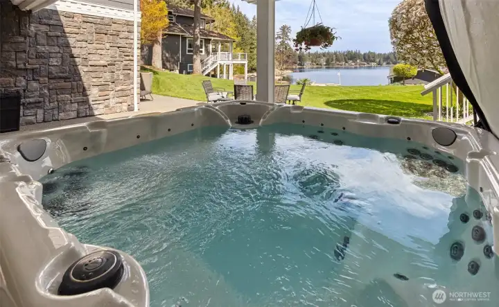 From the hot tub, you’re looking straight out to the lake with a full view of the backyard stretching out in front of you, which makes it very easy to lose track of time out here. The stone accents along the exterior add just enough texture to keep things feeling grounded and intentional. And because this home actually thinks ahead, there’s an outdoor shower right here on the lower patio, perfect for rinsing off after a swim or hosing down muddy feet before heading inside or slipping into the spa.