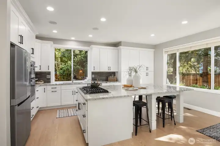 Expansive built-in granite topped buffet center island with storage and breakfast bar, complemented by custom soft-close cabinetry and integrated ambient lighting - perfect for elegant entertaining.