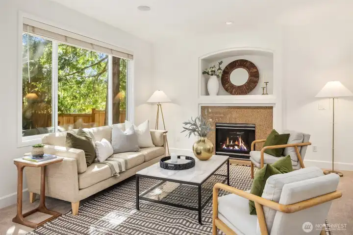 Inviting family room anchored by a cozy gas fireplace, oversized windows, and built-in wall speakers for an immersive living experience