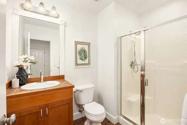 Main Level 3/4 Bath Stylish 3/4 bath featuring ceramic tile flooring and coordinating tile countertops for a clean, cohesive look.