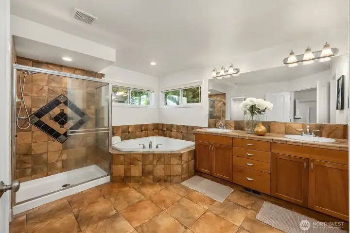 Spa-inspired ensuite with soaking tub, dual vanity, tiled shower surround, and a walk-in closet with custom organization system