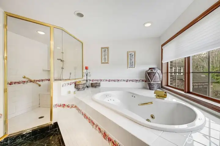 Jetted tub with waterfall facet. Shower with dual shower fixtures and built-in bench seat.