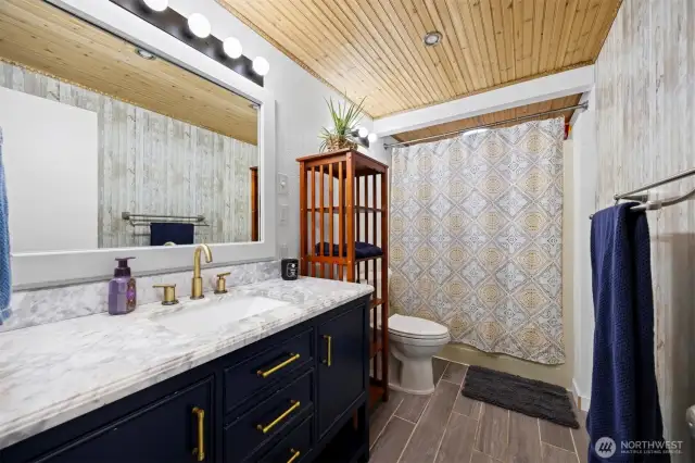The full bath is on the main level and has a tile floor that mimics wood. The celling here is bead-board.