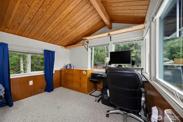 This wood-lined sunroom/office looks out toward the Ted Edwards Park beyond the 5 vehicle garage/carport as well as the swimming pool.