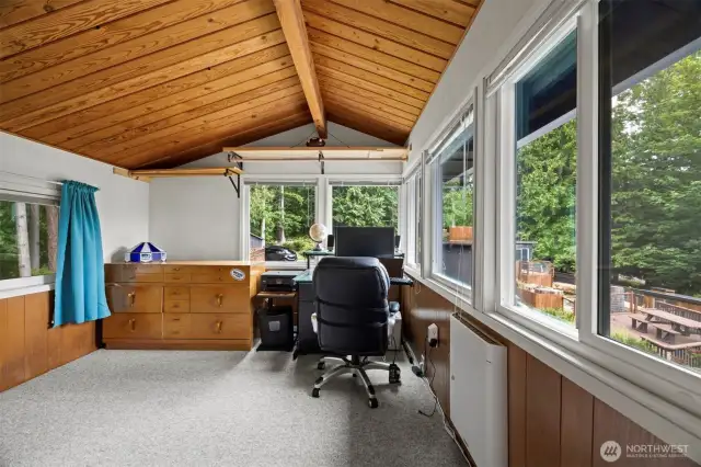 This wood-lined sunroom/office looks out toward the Ted Edwards Park beyond the 5 vehicle garage/carport as well as the swimming pool.