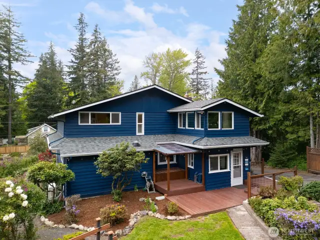 Looking at the rear elevation of the home surrounded by mature landscape.