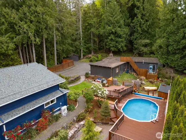 Looking down on to the rear yard with the pool, expansive decks and the 5 vehicle garage/carport and a garden shed beyond that.