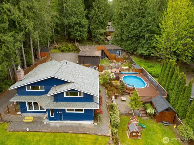 Looking down at the home, the pool with a new pumphouse and the kid's play area with the garage beyond and the park behind that.