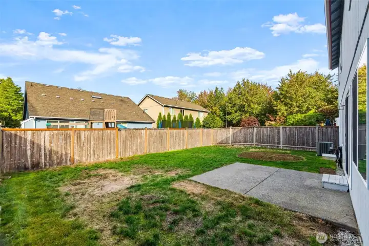 The fenced backyard has lots of room. Notice the a/c unit toward the side of the home.