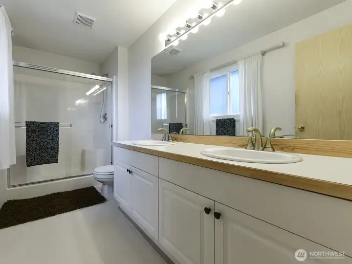 Ensuite primary bath.  Double vanity, privacy film on window lets in natural light.
