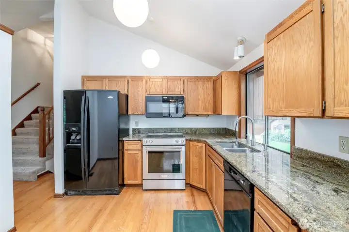 Kitchen with natural hardwood floors, granite countertops and all appliances stay
