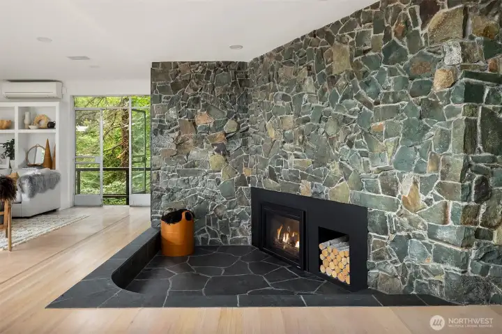 Floor to ceiling sunken fireplace has remote controlled gas fireplace and seating edge covered with slate flagstone and stonework matching the entry way. Floor to ceiling sunken fireplace has remote controlled gas fireplace and seating edge covered with slate flagstone and stonework matching the entry way.