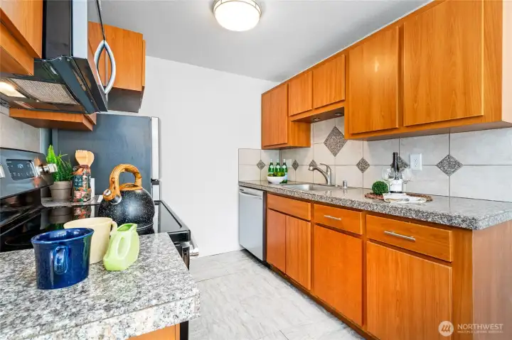 Efficient galley layout with ample cabinets and granite tile countertops.