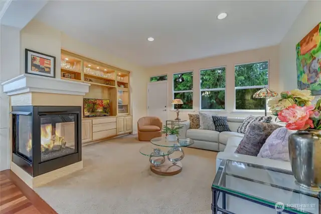 The built-in entertainment center and lighted display cabinet is the focal point of the family room. The trees provide a verdant outlook and the 3-sided fireplace keeps this room cozy during the colder months.