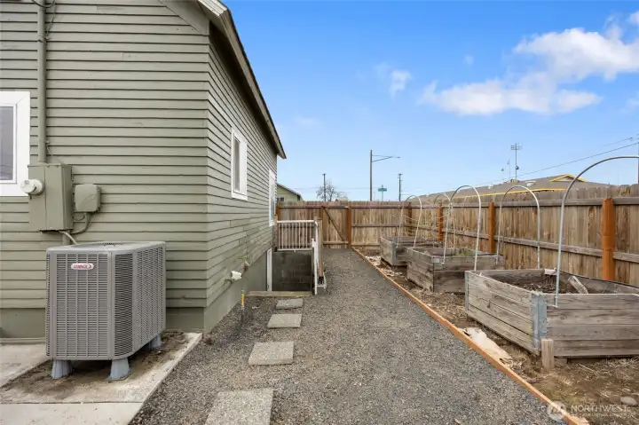 Side yard with gravel path leading to the 3 bedroom door, plus more raised organic beds.