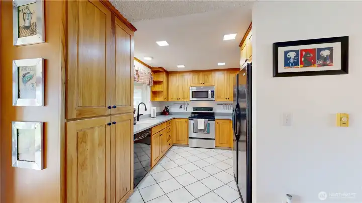 Bright and functional kitchen with wood cabinetry, abundant storage, sleek countertops, stainless steel appliances, and bright recessed lighting.
