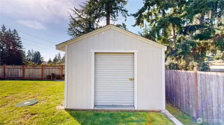Larger shed with a roll-up door offers great potential for a shop, hobby space, or additional storage.
