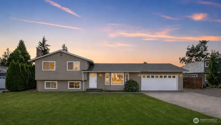 Classic split-level home with a wide driveway, attached two-car garage, and attractive twilight presentation Classic split-level home with a wide driveway, attached two-car garage, and attractive twilight presentation