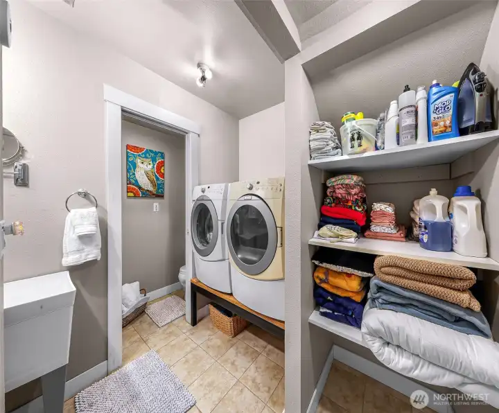 Laundry room includes a utility sink, built-in shelving, and convenient access to the adjacent half bath Laundry room includes a utility sink, built-in shelving, and convenient access to the adjacent half bath
