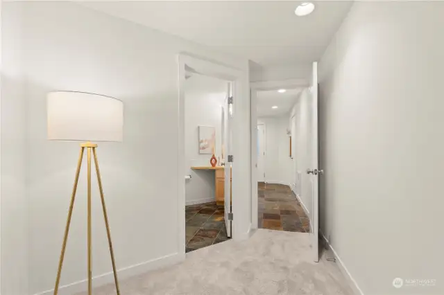 Main level hallway leading to the 3rd bedroom. Full bathroom is through the door on the left.