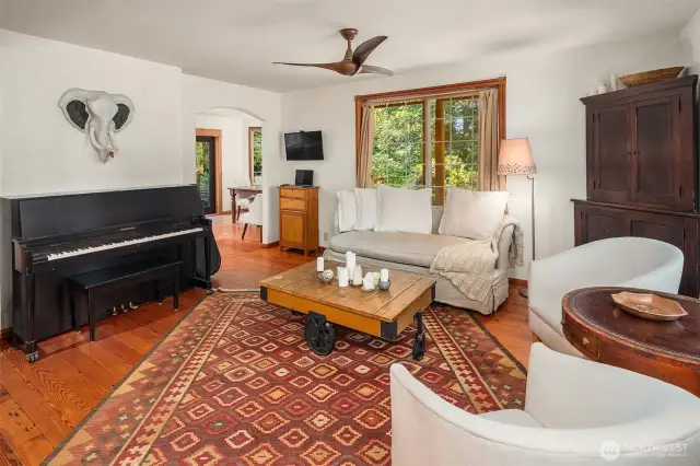 Pine floors warm the spaces throughout the main floor. Dining area can be seen beyond the living room.