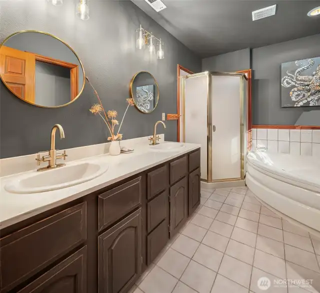 Primary en-suite full bath. Vanity with two sinks, new mirrors, light fixtures and faucets. Tile floors.