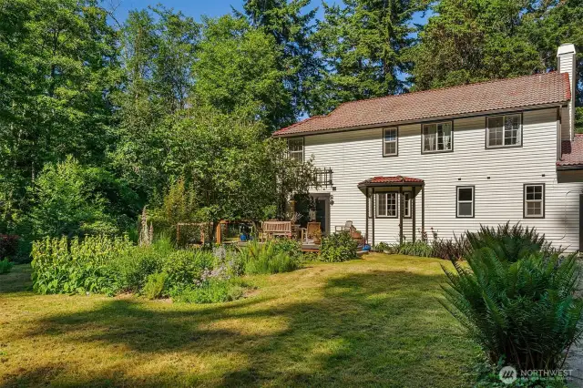 West-facing side of the home looks out over lush gardens and forested hillside.