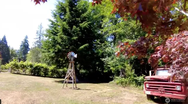 Large front yard has fire pit, small pond and amazing trees!