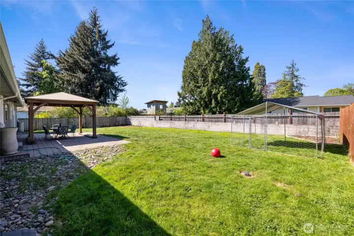 Large fully fenced back yard features gazebo and dog run area
