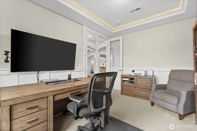 A main-floor office with glass French doors offers the perfect setting for remote work, featuring ample space and natural light to create a functional, bright, and cheerful workspace.